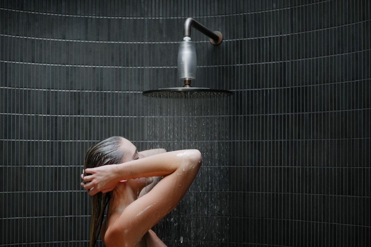 A woman showering with a Fettle Effect shower filter